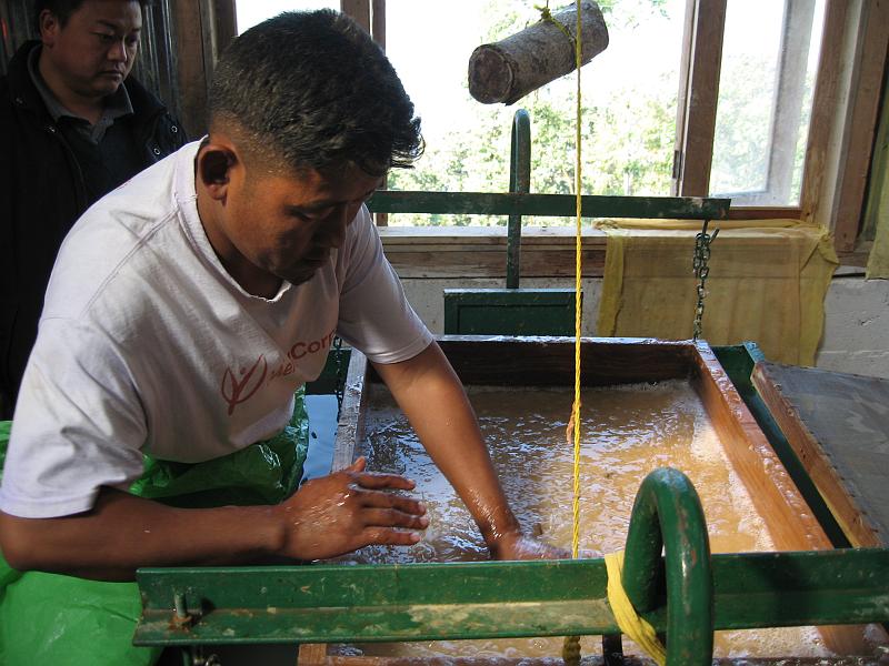 IMG_2880.JPG - This is the boss of the factory. He's sloshing the pulp slurry on to a screen inside the wood frame. The frame and screen is then removed.